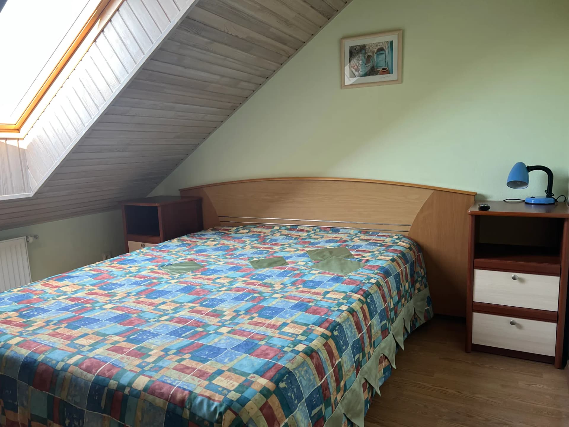 Šeštojo kambario lova mansardoje prie žalios sienos, virš jos stogo langas